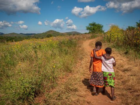 Two children walk down a road in Africa