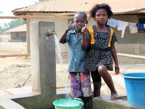 Mary and Abu giving thumbs up in appreciation of safer drinking water provided in their community.JPG