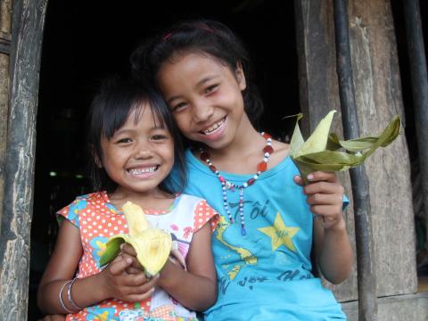 Two Vietnamese children hold flowers at their home