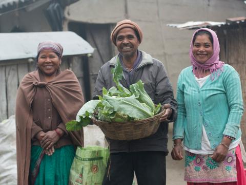 A family holds produce outside of the farm in Nepal