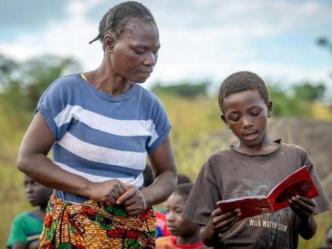 Featured Image: Community reading club volunteer, Jenara Mumbulu, listens to and helps Lightwell, 10, with his reading at a World Vision's reading camp in Zambia. (Photo credit: Laura Reinhardt / World Vision).