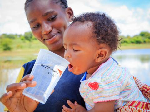 Baby Damian from Mwala, ADP Kenya, is given water from a water project WV implemented in the area.