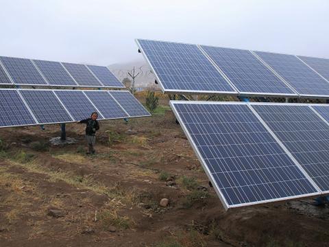 A boy standing next to the solar panels that have been set up by World Vision.