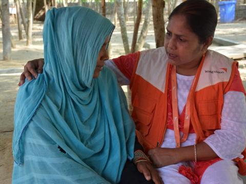 World Vision staffer sits with a Rohingya refugee