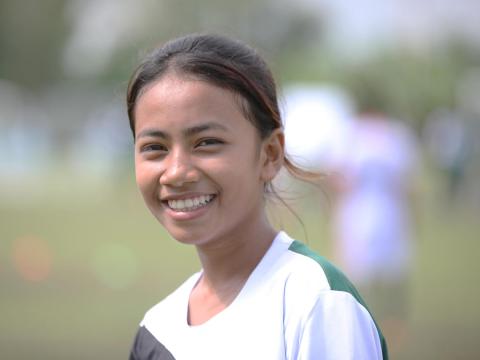 Khmer teenager in football jersey smiles on football pitch