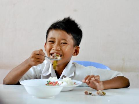 Young Khmer boy eating meal at the table