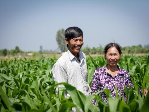 Khmer husband and wife stand in the tall grasses of their corn field