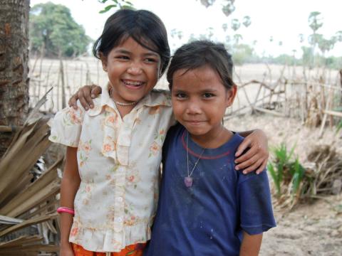 Two Khmer children stand together with their arms around each others shoulders