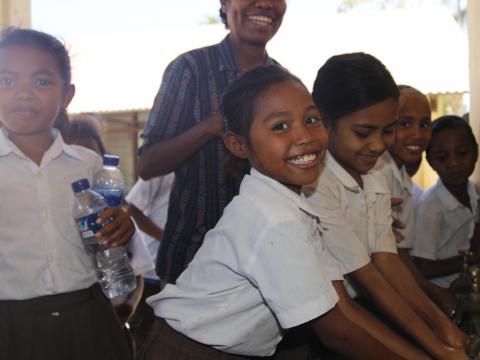 Nine-year-old Nensia happily washes her hands with clean water at her school. Photo: Jaime dos Reis/World Vision