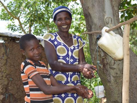 Ruth with her grandchild washing hands next to the toilet they built. © World Vision/Photo by Hellen Owuor