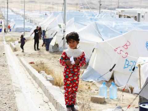 A Syrian refugee stands in front of tents