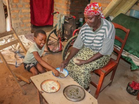 Josephine and her grandchild Maggie eating Nshima-- the staple food in Zambia made from finely ground corn meal, called mealie meal.