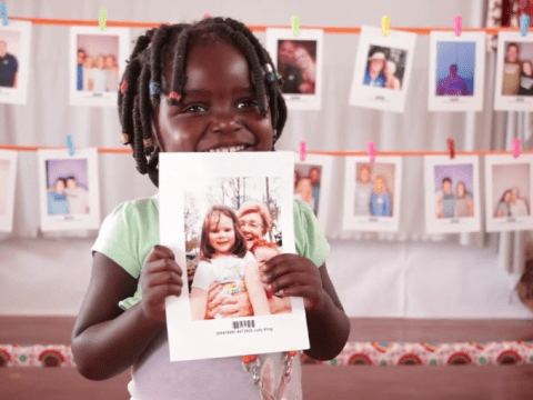 A child holds the picture of the sponsor they chose. 