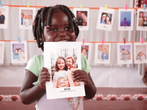 A child holds the picture of the sponsor they chose.