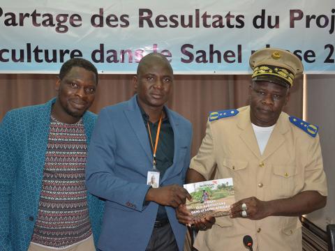 World Vision's ZonalOperations Manager for South and Western Mali, Adama Keita (centre), hands over the final Eco Agricultural report to the chief of Diema Prefecture, Abou Diarra (right).