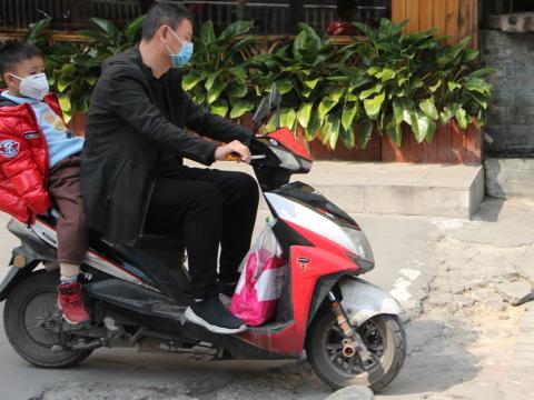 Child and dad in masks on a bike