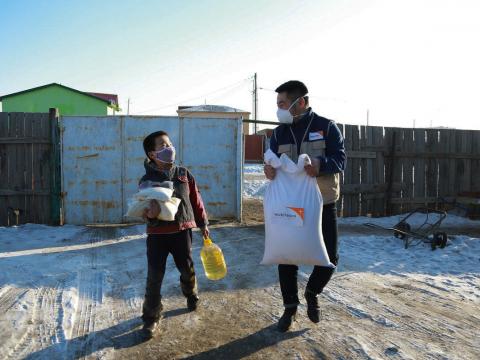 World Vision staff helping child with mask and food distribution during pandemic