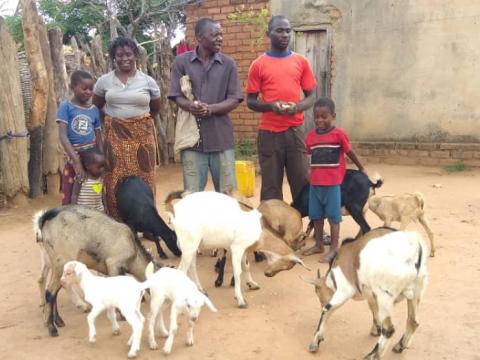 A farmer standing with his family members and goats