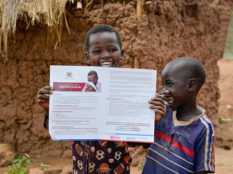 Children in Bidibidi holding a COVID-19 Poster