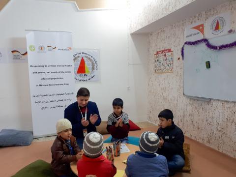 Adil (in the brown jacket to the left of facilitator Muath) participating in group activities in the Child Friendly Space