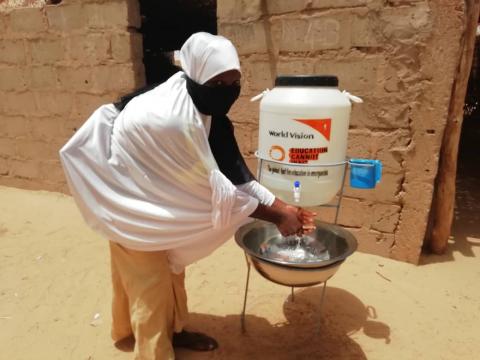 A girl washing her hands near a hygien kit provided by WV