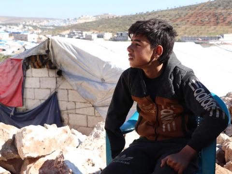 Refugee child sitting in front of tent