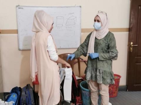 Hiba receiving school materials from World Vision case worker, Maryam. 