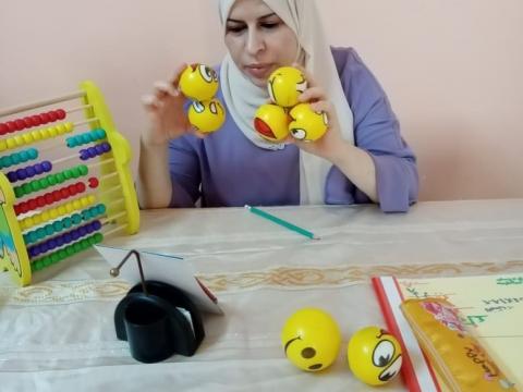 Safaa, the Maths teacher, is using small balls to explain the addition lesson properly.  The teacher is using variable teaching and learning materials to attract the students’ attention.