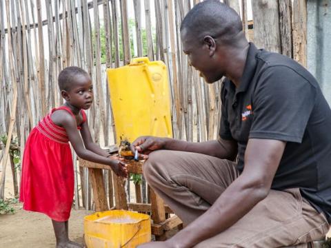 Child washing hands in water 