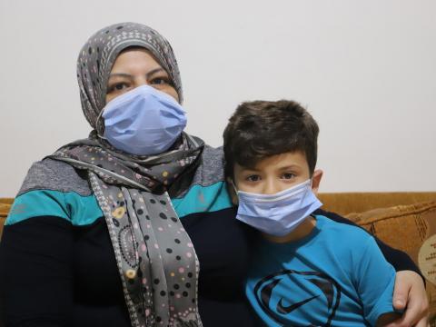 Mum and boy wearning masks on a sofa