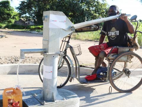 David is showing how he fetch water from the water point with a ramp that allows him to reach the crank through wheelchair