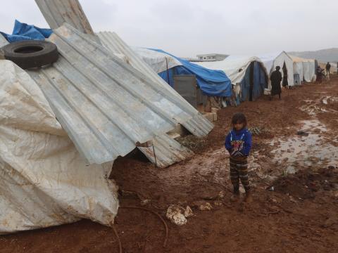 A young girl stands near her tent in a displacement camp in Northwest Syria