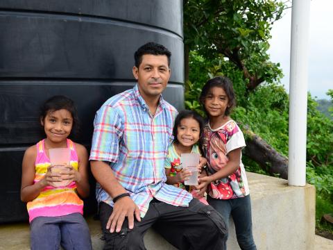 A family sit infront of a water tank
