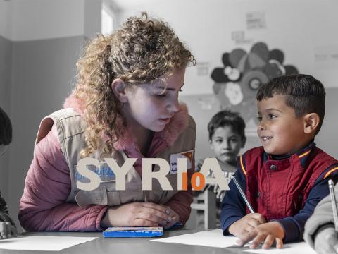 World Vision staff member helps Syrian refugee child