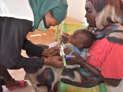 A World Vision nutrition nurse, attends to a child admitted with malnutrition, at a World Vision nutrition centre