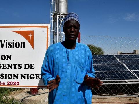 Man in Niger stands infront of Solar pannels that are part of World Vision's WASH programme for displaced people