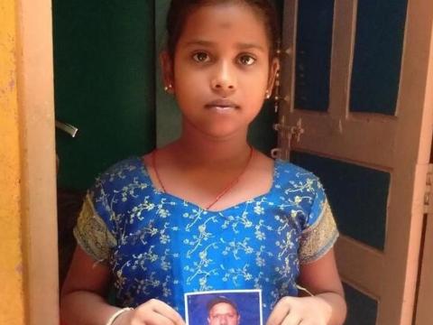 Child in India holds the photograph of her father who passed away from COVID-19