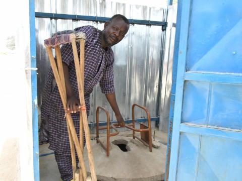 Adamou holding the chair in the latrine