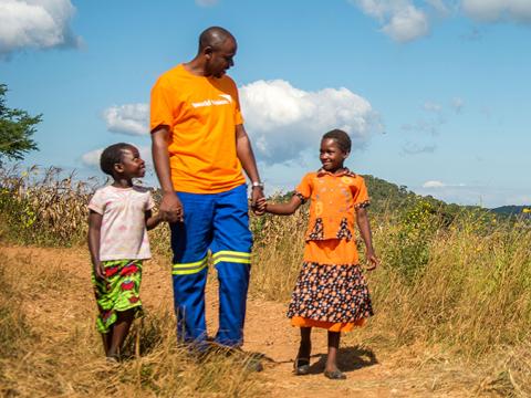 World Vision staff member walks with children in Africa