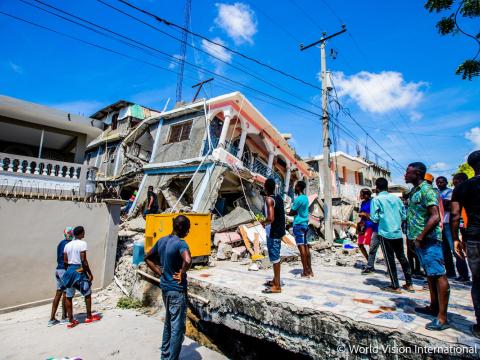 Haitians stand around the wreck of a building damaged in the 2021 earthquake
