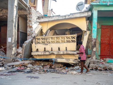 Woman walks by collapsed house in Haiti following earthquake