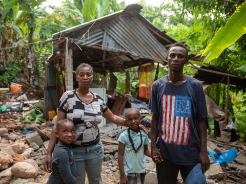 Family that lost their home in Haiti earthquake stands in front of the rubble
