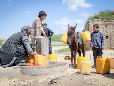 boys and men fill water containers at clean water point in Afghanistan