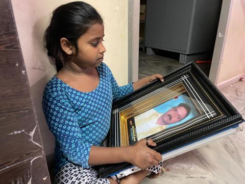 9-year-old Ashmitha looks at a picture of her father. This will be her first Christmas without him