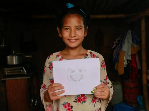 Sponsored child holds up a picture she drew after her father died in Nepal