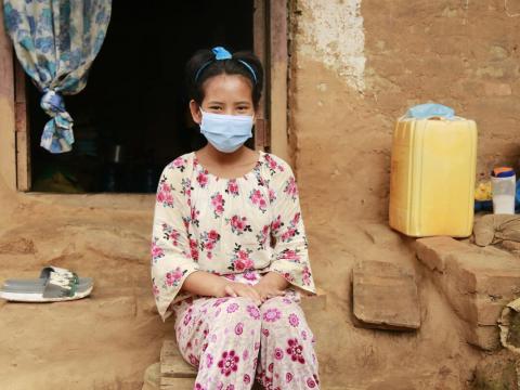 Sponsored child sits on front steps of her home after her father died