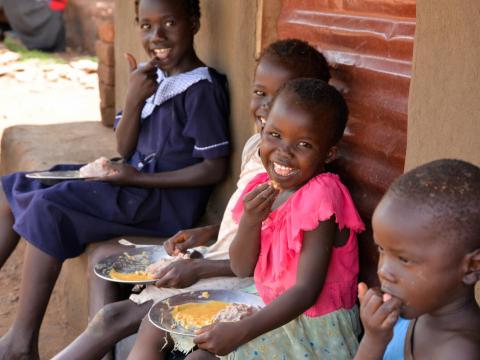 Young girl eats food with her family in front of their home