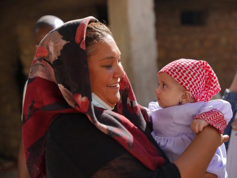 World Vision Iraq Response Director Nicole Peter meeting a newly baptised Yazidi child in her purple dress and her special red and white checked head-scarf. Photo: Shwan Mohamed Amin