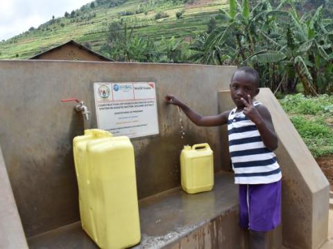 Kevin smiles as he draws clean water from a WSS constructed by World Vision