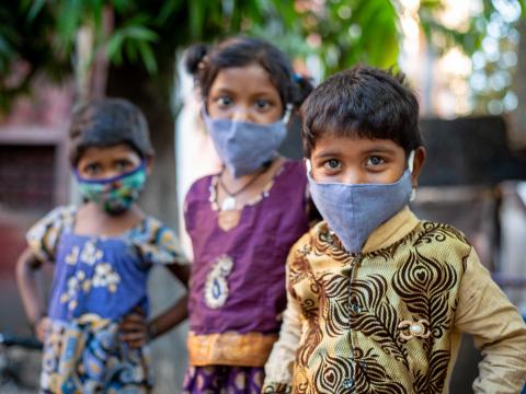 Three children in India wearing masks looking at the camera